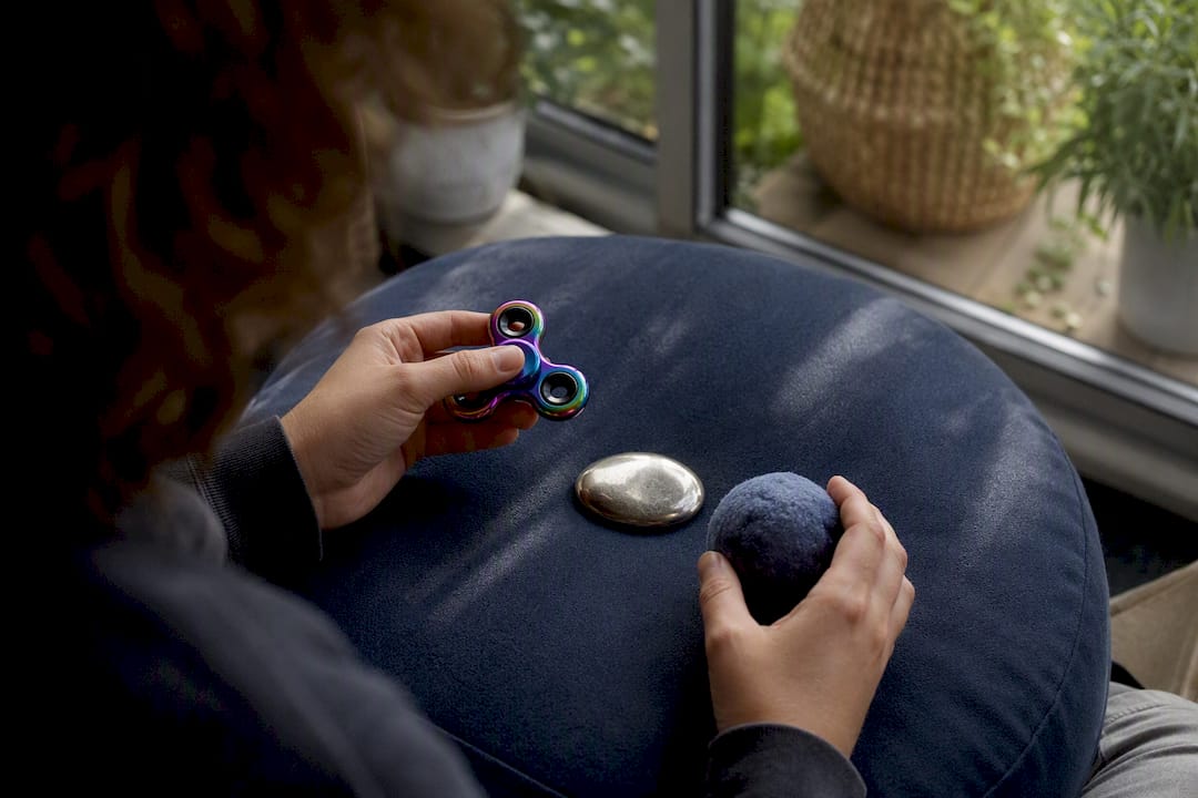 Hands using sensory stress-relief tools on table