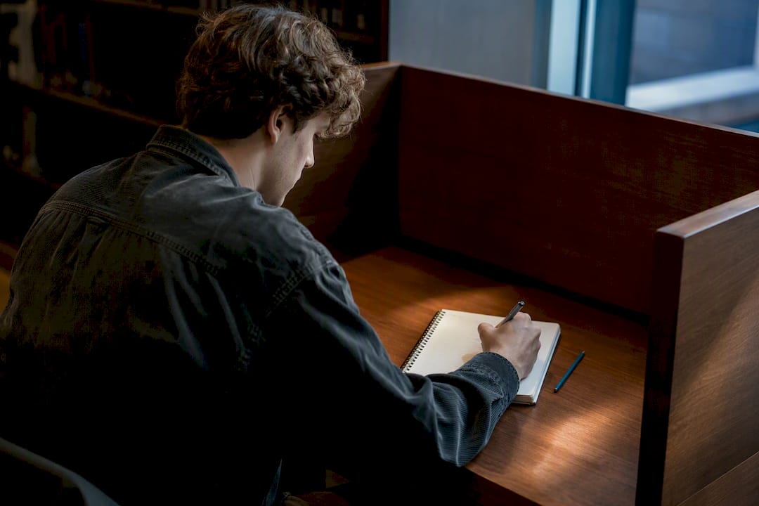 Student writing study steps in notebook